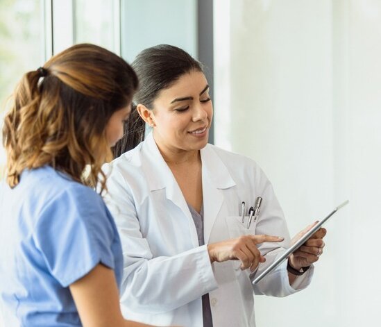 Zwei Gesundheitsfachpersonen unterschreiben auf einem Tablet.